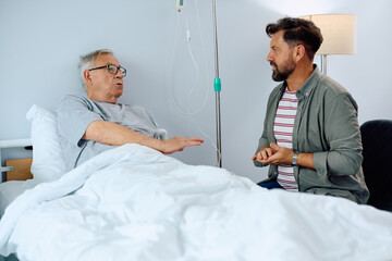 Senior man talks to his son while recovering in hospital.