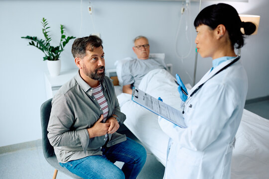 Man talks to female Japanese doctor while visiting his senior father in hospital.