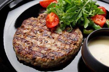 mouthwatering grilled pork steak topped with savory sauce, peppery arugula and ripe tomatoes
