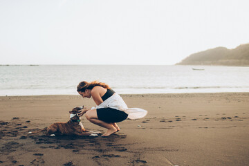 woman petting her dog on the beach