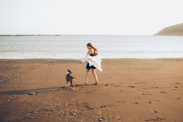 woman running with dog on the beach