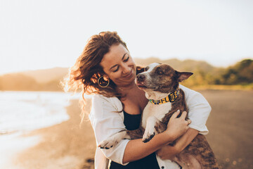 woman hugging her dog on the beach