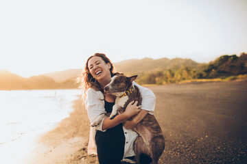 woman hugging her dog on the beach - Powered by Adobe