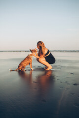 woman petting her dog on the beach