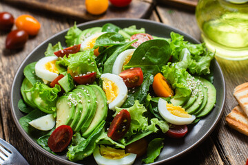 Salad with spinach, avocado, tomatoes in a plate. Vegetarian salad