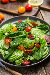 Salad with spinach, avocado, tomatoes in a plate. Vegetarian salad