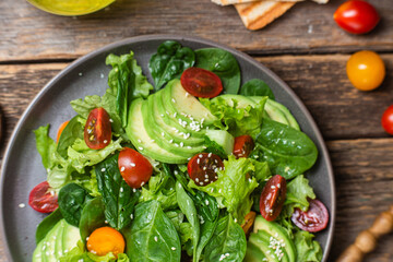 Salad with spinach, avocado, tomatoes in a plate. Vegetarian salad