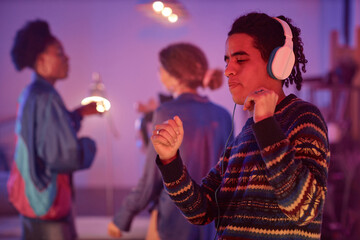 Waist up portrait of ethnic young man dancing with headphones on while enjoying silent disco party...