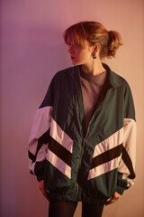 Vertical portrait of young girl wearing oversize retro jacket in 80s aesthetic style, side view