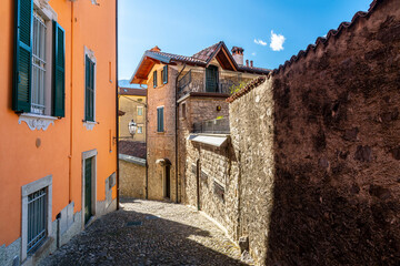 An empty hillside alley of stone and stucco buildings in the historic center of Varenna, Italy, a small village on the shores of Lake Como.