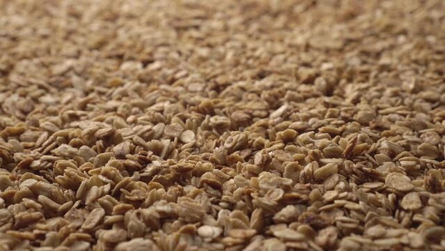 Oatmeal or crunchies form a slowly rotating textured background. Concept of healthy food - cereal breakfast. Close-up, 45 degree angle view. Copy space for advertising text