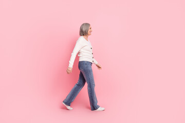 Full body profile portrait of pretty positive person good mood walking empty space ad isolated on pink color background © deagreez