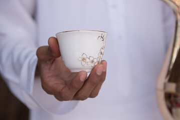a man holding an arabian coffe cup