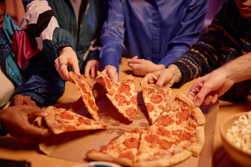 Closeup of diverse group of friends sharing pizza with pepperoni at house party 80s style, copy...