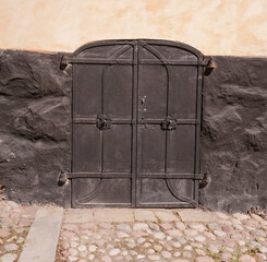 Old black steel hatch doors in a stone wall, a sunny summer day in Stockholm