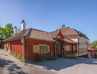 Park street with old craftsman houses and entrance to a café, a sunny summer day in Stockholm