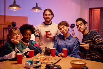 Diverse group of young people looking at camera at house party 80s style