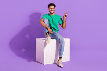 Full length photo of young man directing finger empty space useful tips sit platform brand promoter...