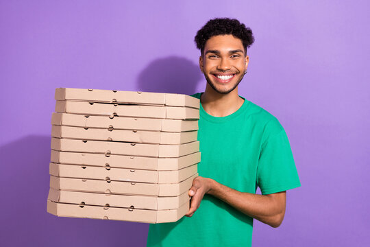 Photo of attractive funky guy dressed green t-shirt delivering pizza boxes pile stack isolated violet color background
