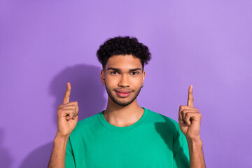 Photo of funny cool nice youngster guy direct fingers up empty space wear green shirt isolated purple pastel color background