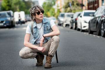Non-binary person in squat position on the road.