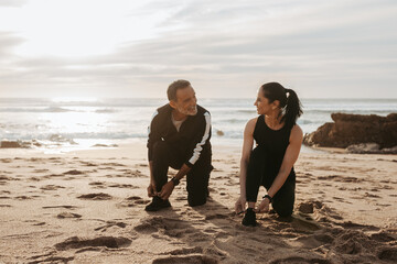 Smiling mature european man and woman tying shoelaces for start to jogging, enjoy workout together