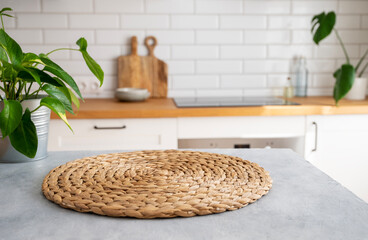Wooden blue table top with flower pot and napkin against blurred white kitchen with cutting board in scandinavian style