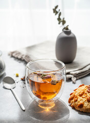 A glass of herbal tea and homemade cookies on the background of a window with morning sunlight.