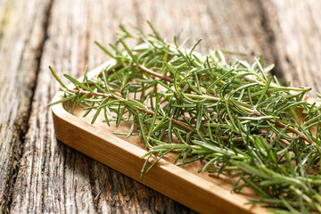 fresh organic freshly picked rosemary with dew or rain drops on top of rustic farmhouse wooden table, selective focus