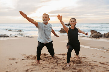 Smiling mature european woman and man in sportswear practice yoga, meditate, enjoy workout together