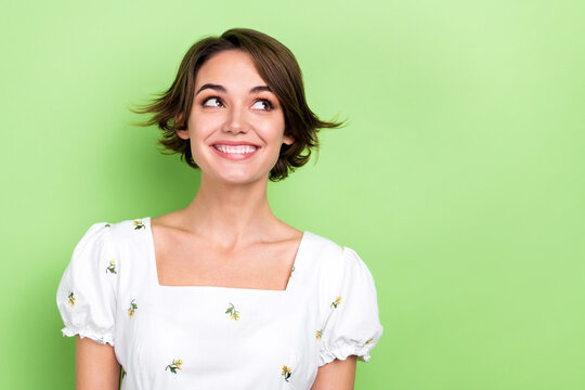 Photo portrait of funny lovely girl look side empty space mischief mood beaming smile isolated pastel green color background