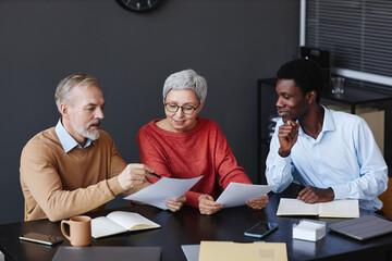 Diverse group of business people with senior workers collaborating on project together in office