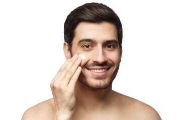 Young man spreading face cream with fingers as part of morning selfcare routine