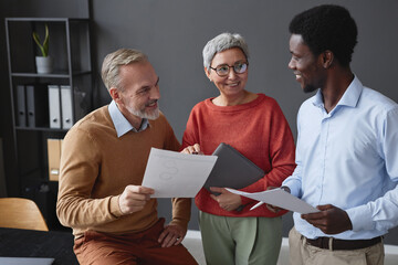 Diverse group of business people with smiling senior workers collaborating on project