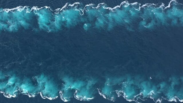 Aerial top down view of water foam trace with nice deep blue shade of ocean. Beautiful white trail on the sea surface behind a large powerful ship. Propwash
