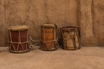Collection of ancient vintage wooden drums near clay walls in heritage village.Percussion oriental musical instruments.