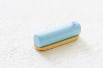 Vegan Blue Matcha cream dessert bar decorated with a small flower. On cookie. Creamy dessert with the addition of blue powder of butterfly pea flowers. White background. Close up