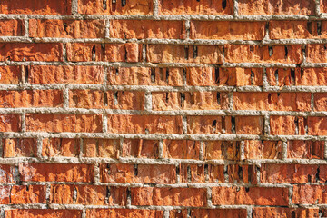 Old weathered half-damaged brick wall texture with cement seams. Background close-up.