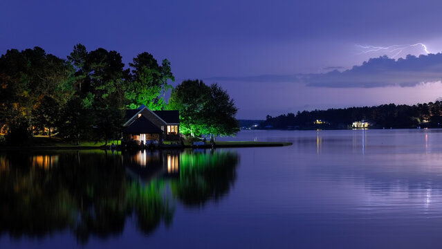 Summertime night photo of home with lake reflection and lightning bolt
