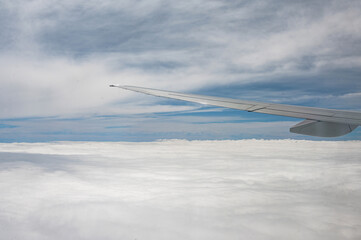 Dramatic view from commercial airplane window with blue sky, many heavy rain clouds and part of the wing. Sky of Brazil, region of São Paulo.