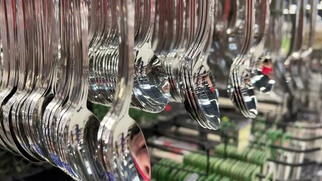 New expensive cutlery - spoons and forks hanging on the counter in the crockery store or tableware shop. Close-up