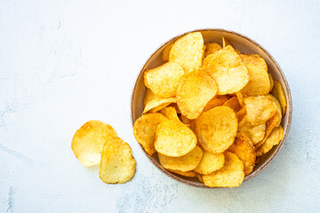 Chips in craft bowl on white table. Top view with copy space.