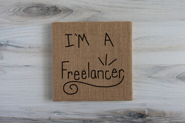 I'm a freelancer, hand written sign on brown neutral burlap canvas