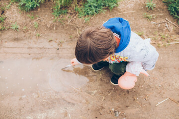 child playing in a mud puddle - obrazy, fototapety, plakaty