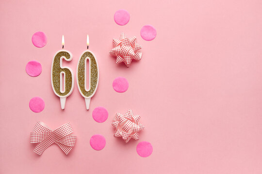 Number 60 on pastel pink background with festive decor. Happy birthday candles. The concept of celebrating a birthday, anniversary, important date, holiday. Copy space. Banner