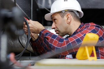 male electrician httesting power supply in roof space