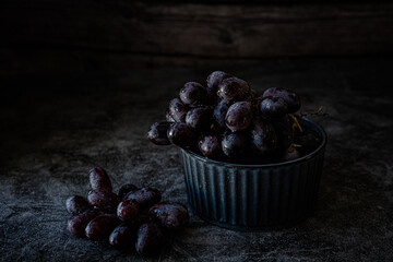 Obraz premium Bowl with black grapes on dark background 