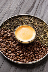 Composition of green tea, coffee beans and coffee in a cup on a dark background.