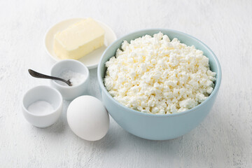 Ingredients: cottage cheese, egg, butter, salt, soda for cooking homemade melted cheese on a light gray background
