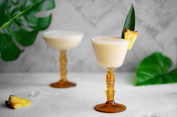 Refreshing summer Piña colada (Pina Colada) cocktail with a piece and a leaf of pineapple as a...